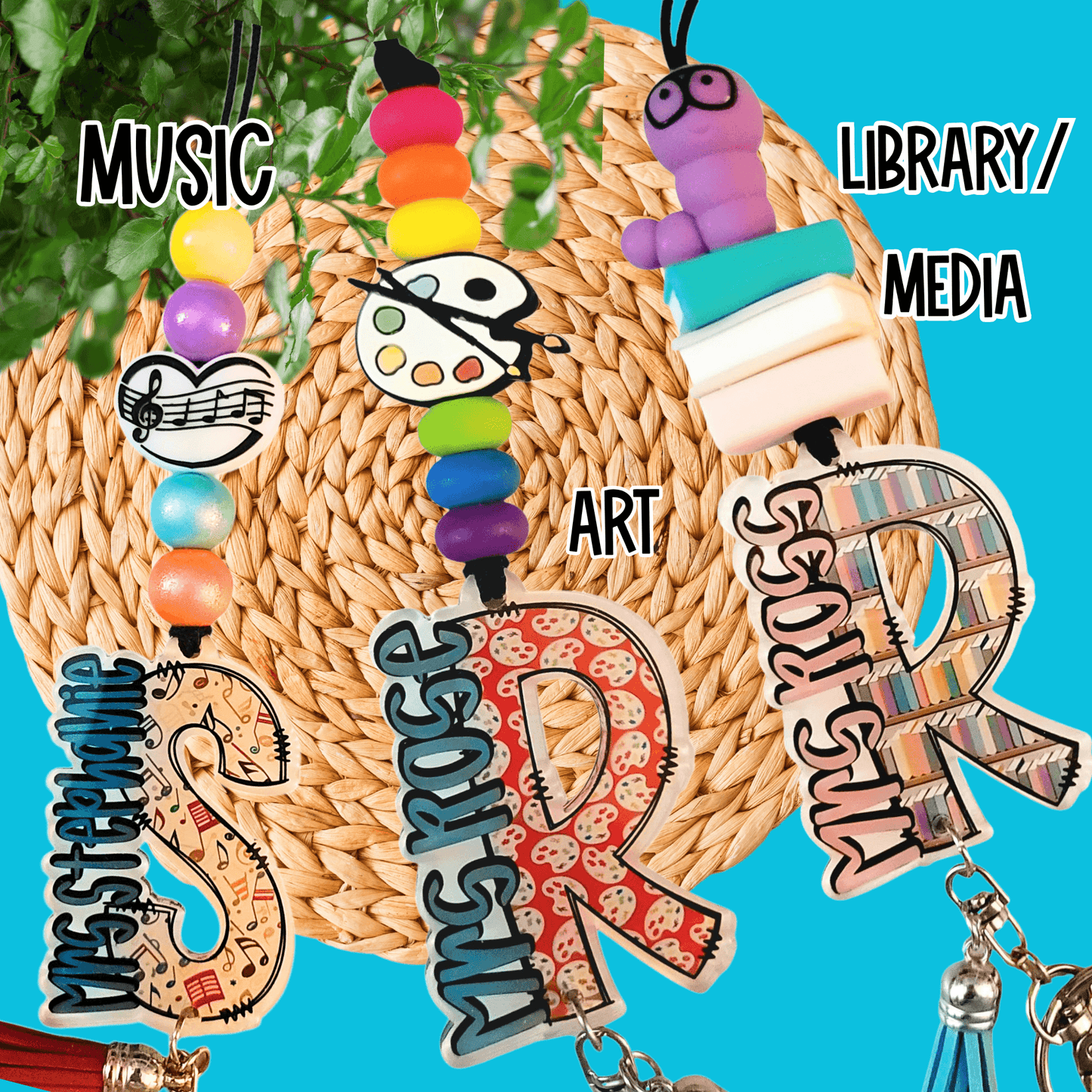 Colorful teacher-themed keychains for music, art, and library media with beads and icons on woven mat