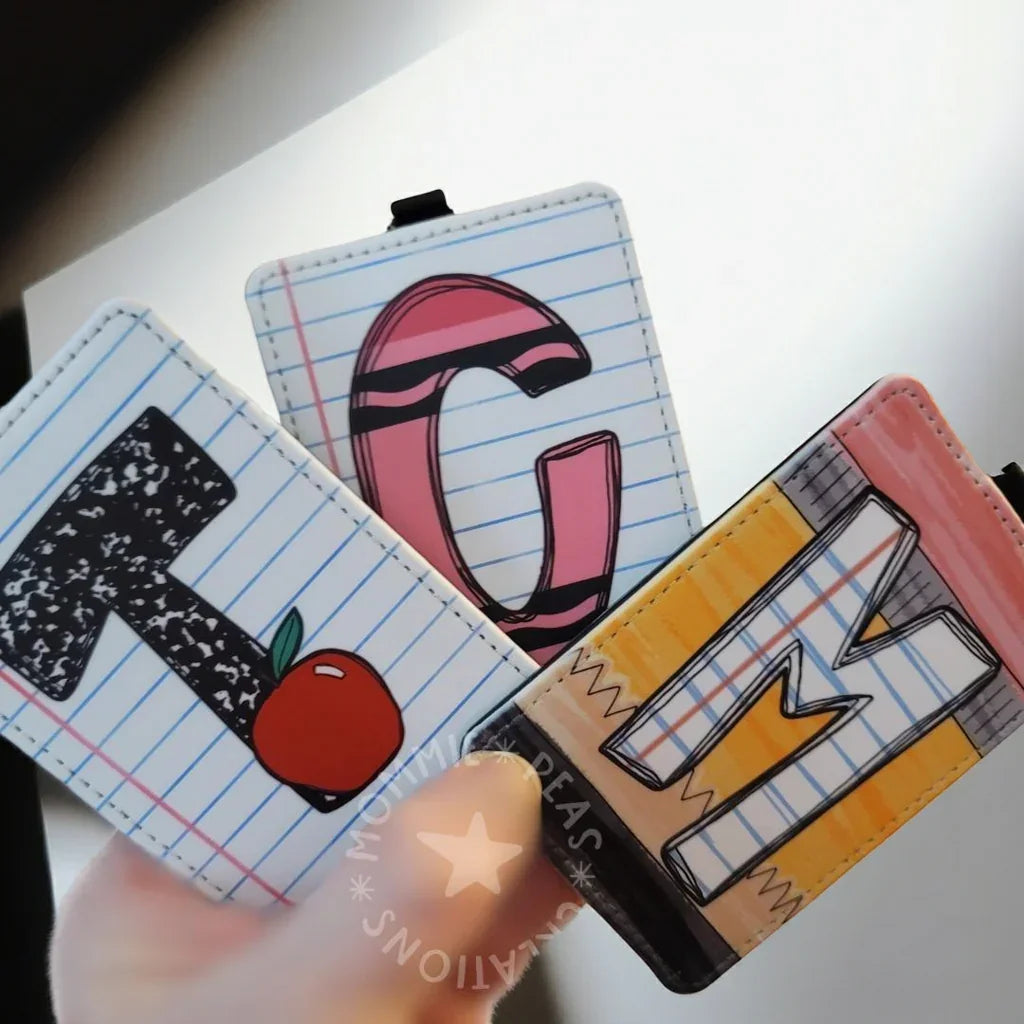 Colorful handmade alphabet badge reels with notebook, pencil, and apple designs, teacher gift