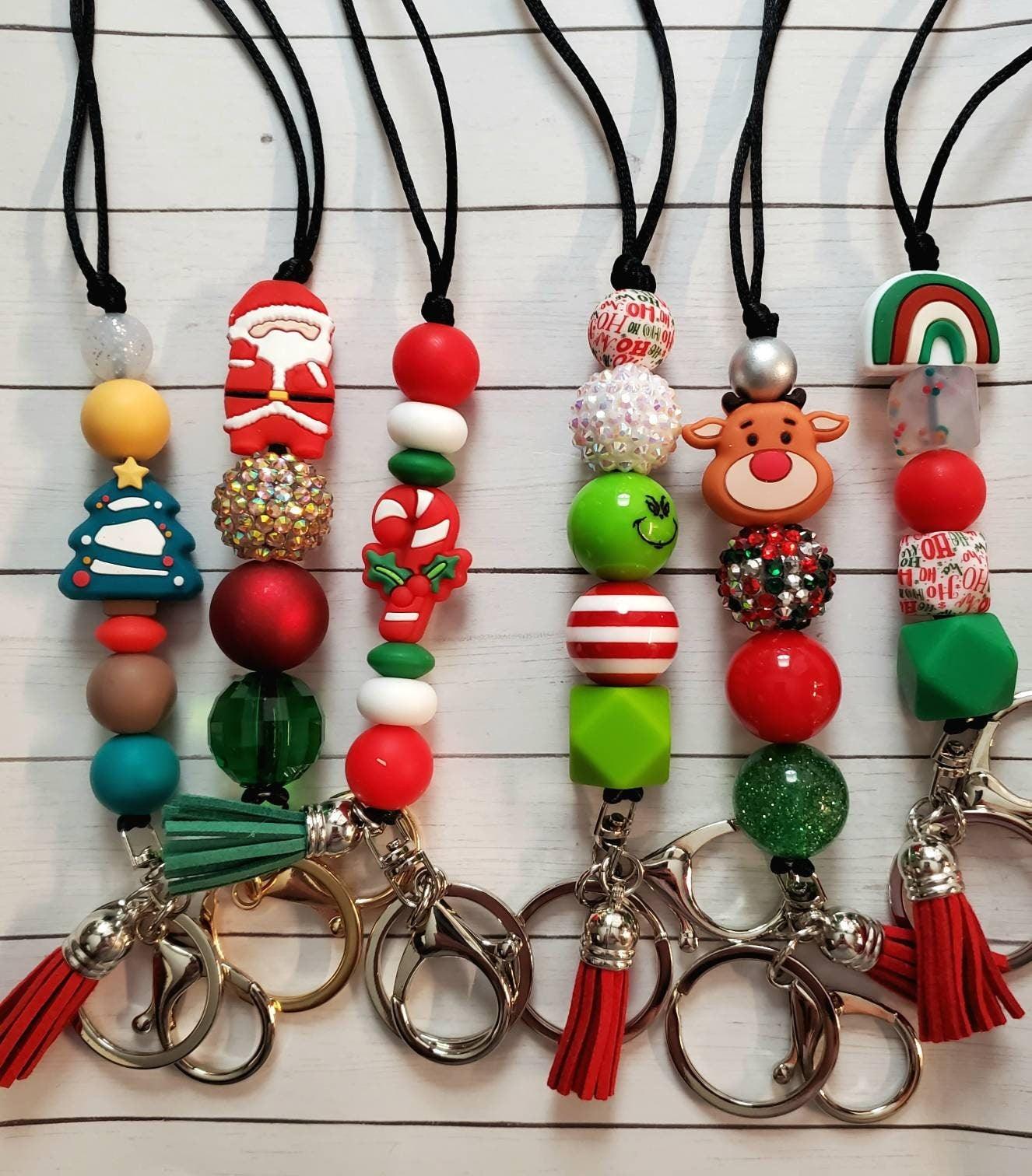 Five festive Christmas keychains with beads including Santa, Christmas tree, candy cane, Grinch, reindeer, rainbow, and tassels
