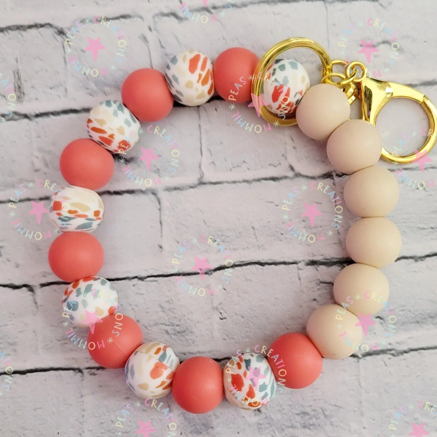 Handmade beaded keychain with peach, cream, and multicolor leopard print beads, gold clasp.