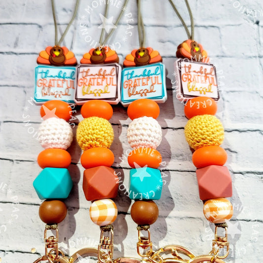 Handmade gifts featuring colorful beaded lanyards with turkey and thankful charms in orange, yellow, turquoise, and brown.