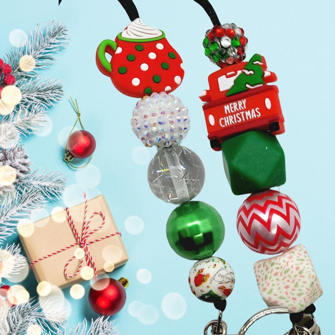 Colorful Christmas-themed keychains with festive beads and charms on a blue background with gift and pine branches