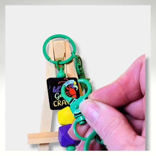 Mommie Peas Creations Mardi Gras beaded keychain with crawfish charm, purple, green, and yellow beads, and green clasp.