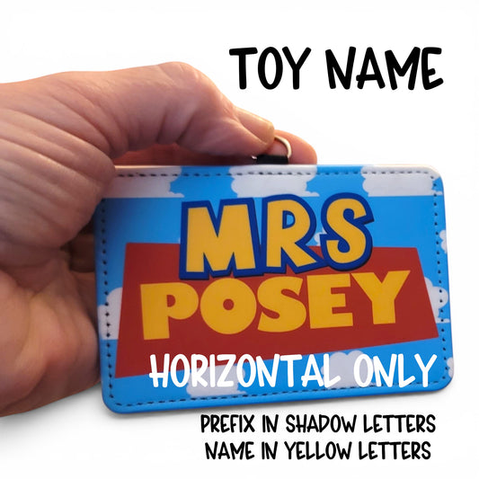 Mommie Peas Creations personalized Toy Story style ID holder with blue cloudy sky background and yellow name text.