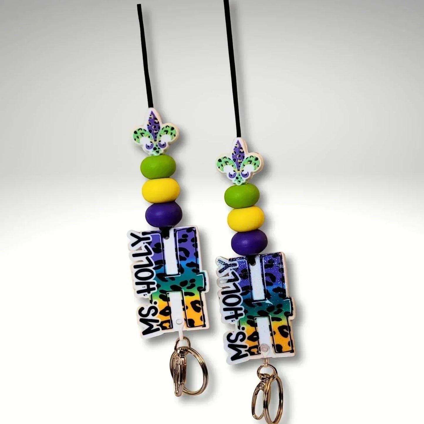 Mommie Peas Creations Mardi Gras lanyard with purple, green, and gold beads, fleur de lis charm, and personalized initial.