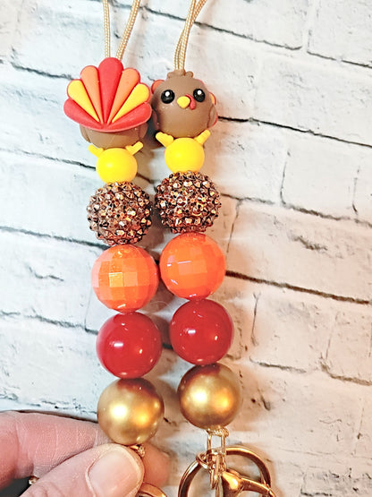 a pair of colorful beaded keychains with a bird-shaped charm on each.