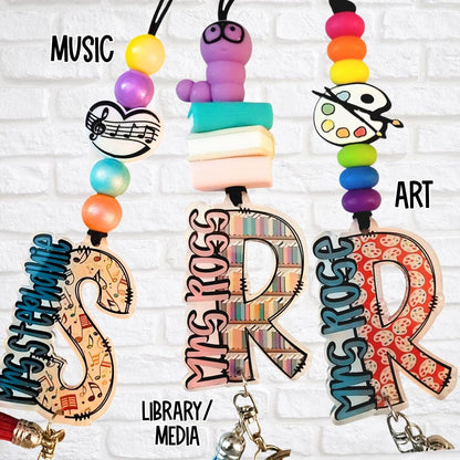 Music, library, and art-themed teacher lanyards with vibrant beads and customized monogram letters for Mrs. Stephanie, Mrs. Ross, and Ms. Rose.