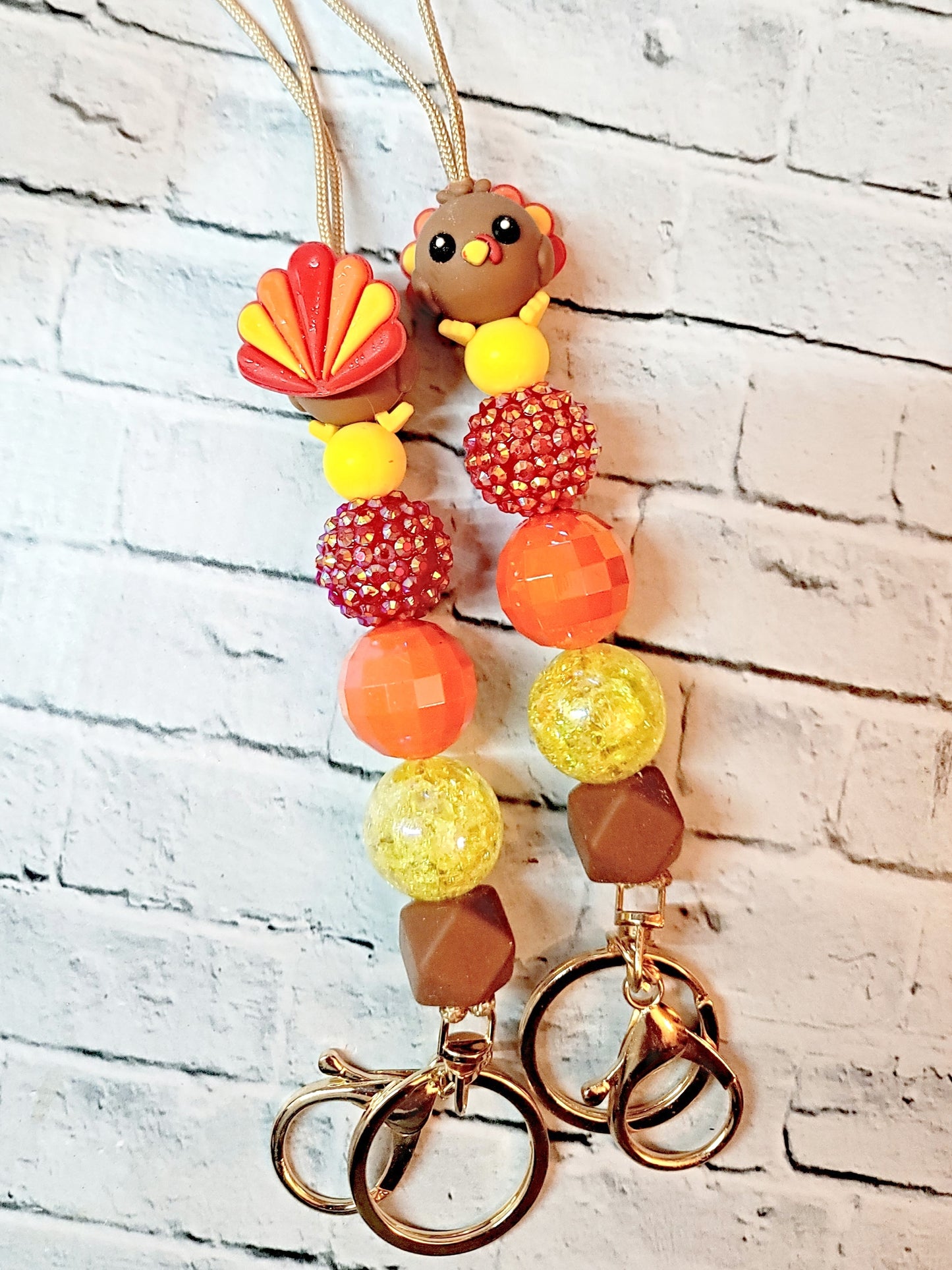 a pair of colorful beaded keychains with a turkey-themed charm.