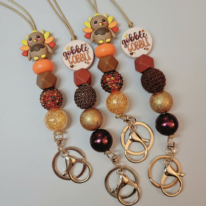 Keychains with fall-themed designs on a textured surface