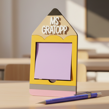 Pencil-shaped sticky note holder with 'MS GRATOPP' text and a pen on a gray background
