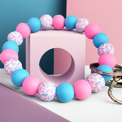 Colorful beaded bracelet with pink, blue, and patterned beads on a geometric pastel background