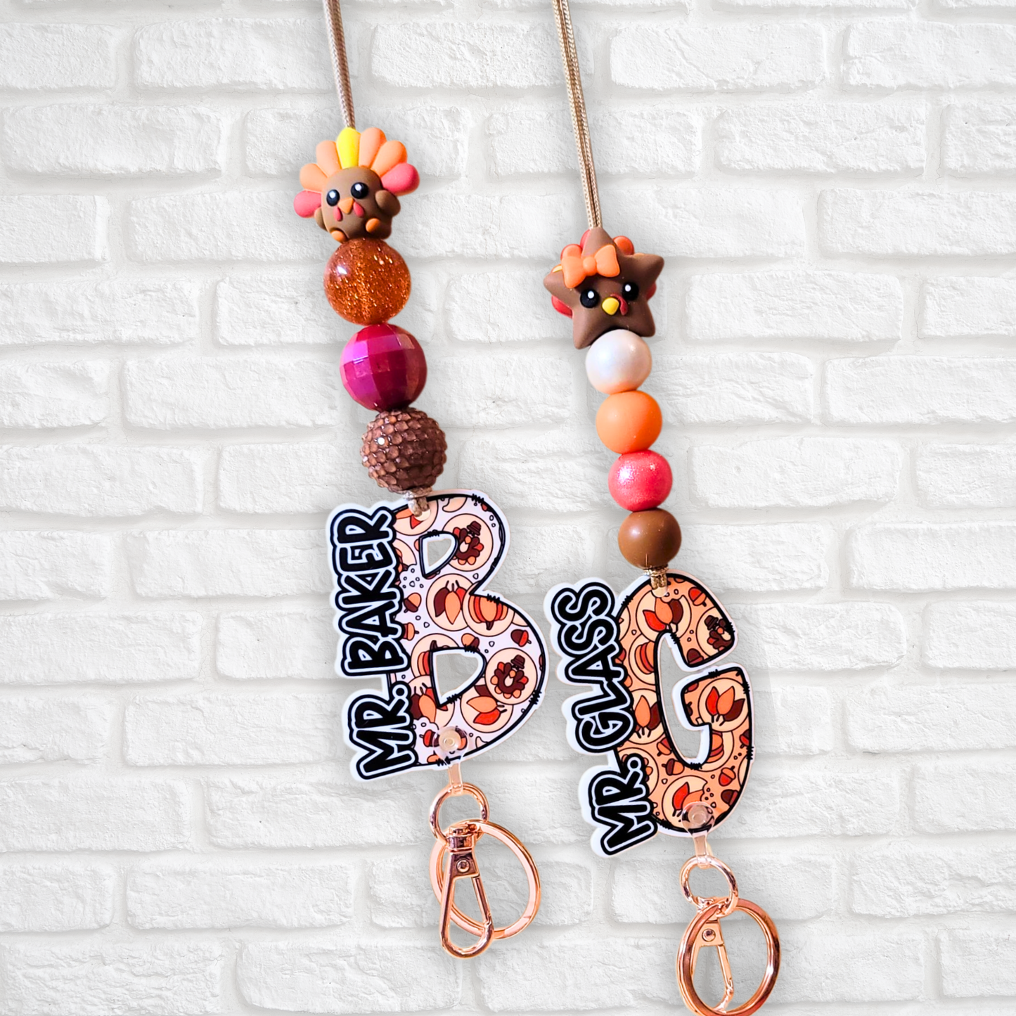 Two festive keychains with autumn-themed beads and charms, labeled Mr. Baker and Mr. Glass
