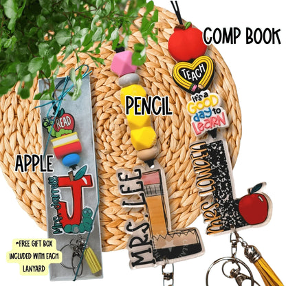 Colorful handmade teacher lanyards with apple, pencil, and composition book charms on woven mat