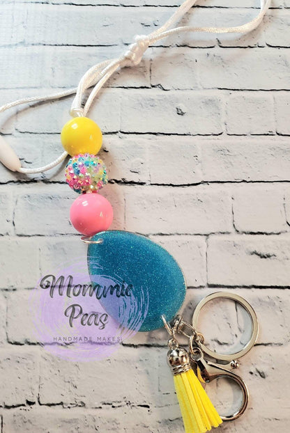 Handmade keychain with blue glitter resin pendant, colorful beads, yellow tassel, and silver keyring