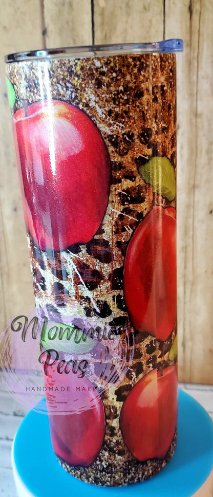 Tumbler with red apple design and brown textured background on blue surface