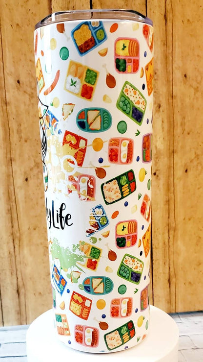 Tall white tumbler with colorful bento box meal illustrations on wooden background