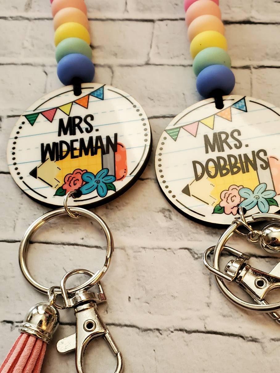 Personalized teacher keychains with colorful beads, names Mrs. Wideman and Mrs. Dobbins, decorative flowers.