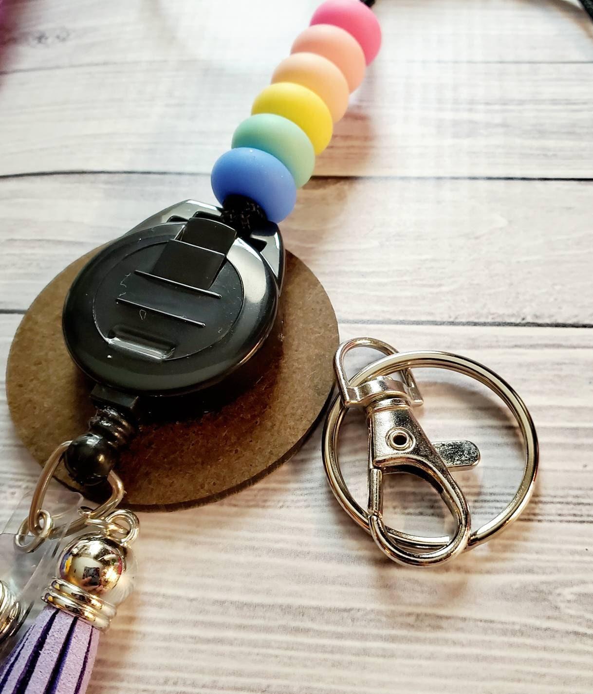 Retractable badge holder with rainbow silicone beads and silver key ring on wooden surface