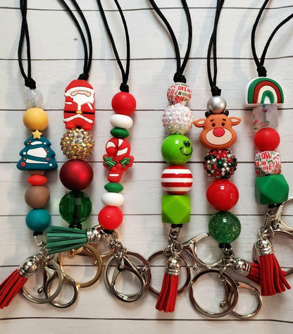 Five festive Christmas keychains with beads including Santa, Christmas tree, candy cane, Grinch, reindeer, rainbow, and tassels