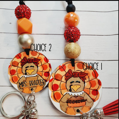 Two handmade turkey keychains with orange, gold, and red beads on wooden background, labeled Choice 1 and Choice 2