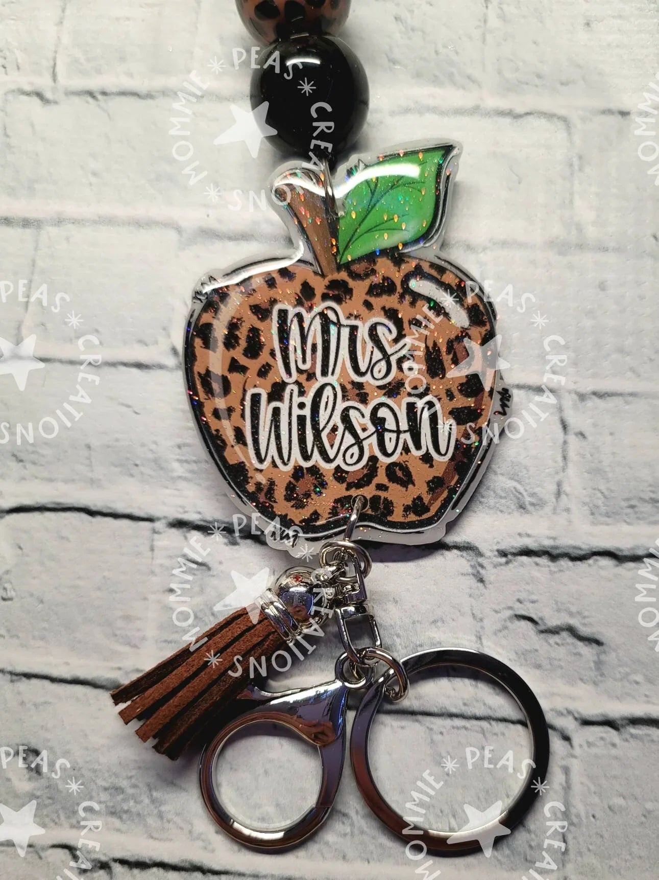 Handmade leopard print apple keychain with green leaf, beads, brown tassel, and scissors charm