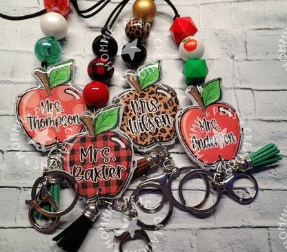 Handmade personalized apple-shaped lanyard keychains in red, plaid, and leopard print with colorful beads, unique custom teacher gifts.
