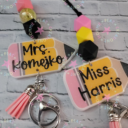 Personalized pencil-shaped keychains with names Mrs. Komejko and Miss Harris, colorful beads and pink tassels