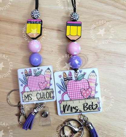 Personalized teacher badge reels with pencil charms, purple beads, and apple school supplies design