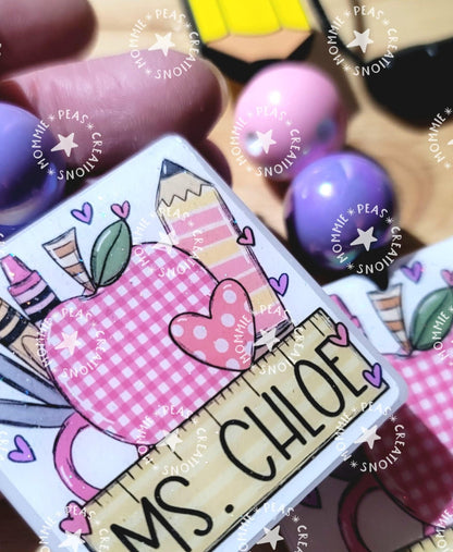 Personalized wooden peg doll with Ms. Chloe name tag and pink school themed illustration