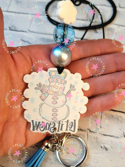 Hand holding winter-themed snowman keychain with blue and pearl beads, tassel, and keyring