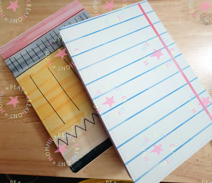 Two notebooks on a wooden surface, one designed like a yellow pencil and the other like lined notebook paper