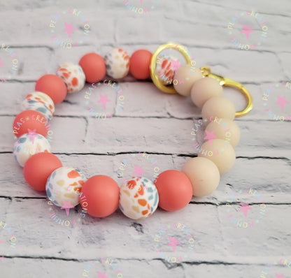 Silicone beaded keychain with coral, beige, and multicolored terrazzo beads on a white wooden surface