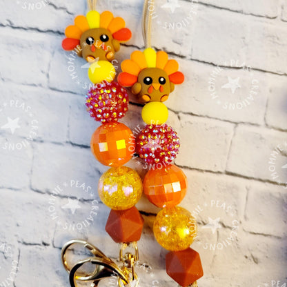 Handmade keychains with colorful turkey charms and assorted orange, yellow, and brown beads