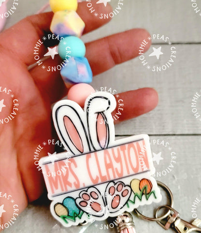 Hand holding colorful beaded keychain with bunny ears, paw prints, and name Mrs. Clayton