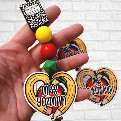 Hand holding custom teacher keychain with pencils, apple, beads, and 'Mrs. Yozman' name tag