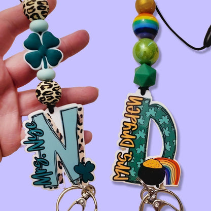 Hand holding custom keychain with leprechaun shamrock and leopard print beads, next to St. Patrick's themed keychain