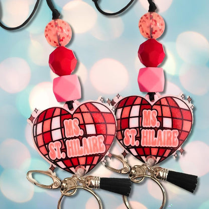 Colorful heart-shaped keychains with Ms. St. Hilaire text, red and pink beads, and black tassels