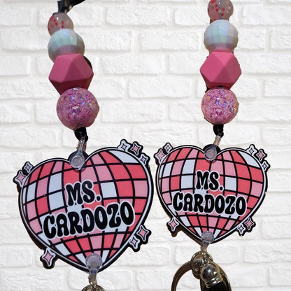 Two pink heart-shaped badge holders with Ms. Cardozo text, decorated with pink and white beads on lanyards