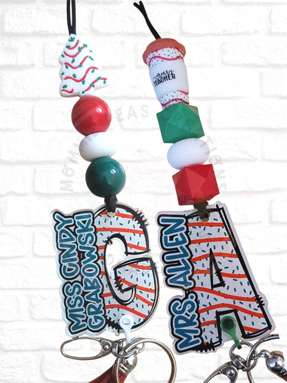 Christmas-themed teacher keychains with red, white, green beads and holiday charms on a brick wall background