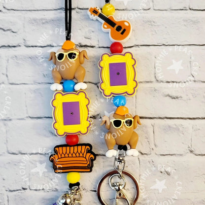 Mommie Peas Creations Fall Turkey Lanyard with Friends-themed charms: turkey, picture frame, couch, and guitar. Features silicone beads and a breakaway clasp.