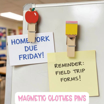 Mommie Peas Creations hand-painted wooden clothespin magnets shaped like an apple and a pencil, holding notes on a whiteboard.