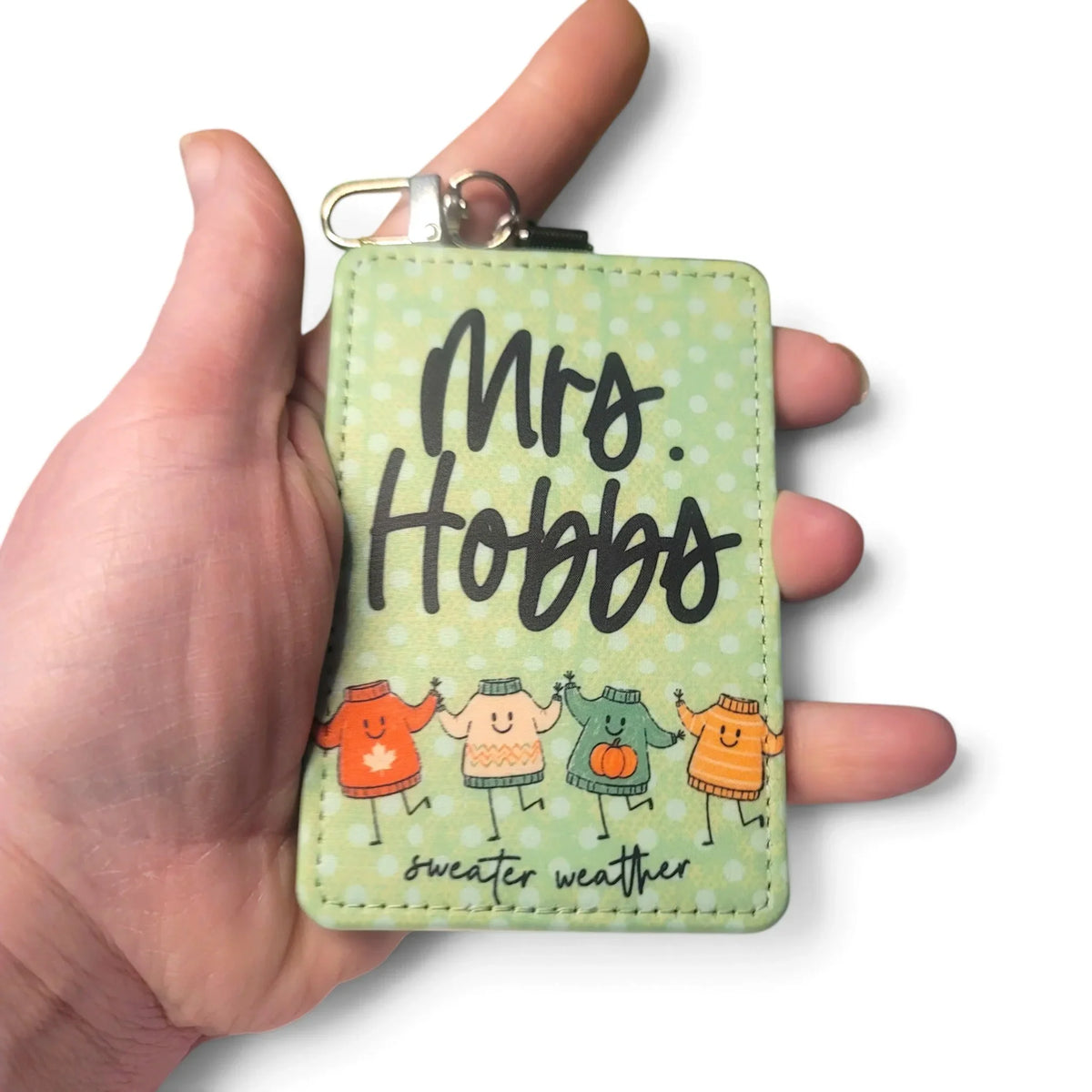 Handmade Mommie Peas Creations green polka dot badge holder with cozy sweaters illustration.
