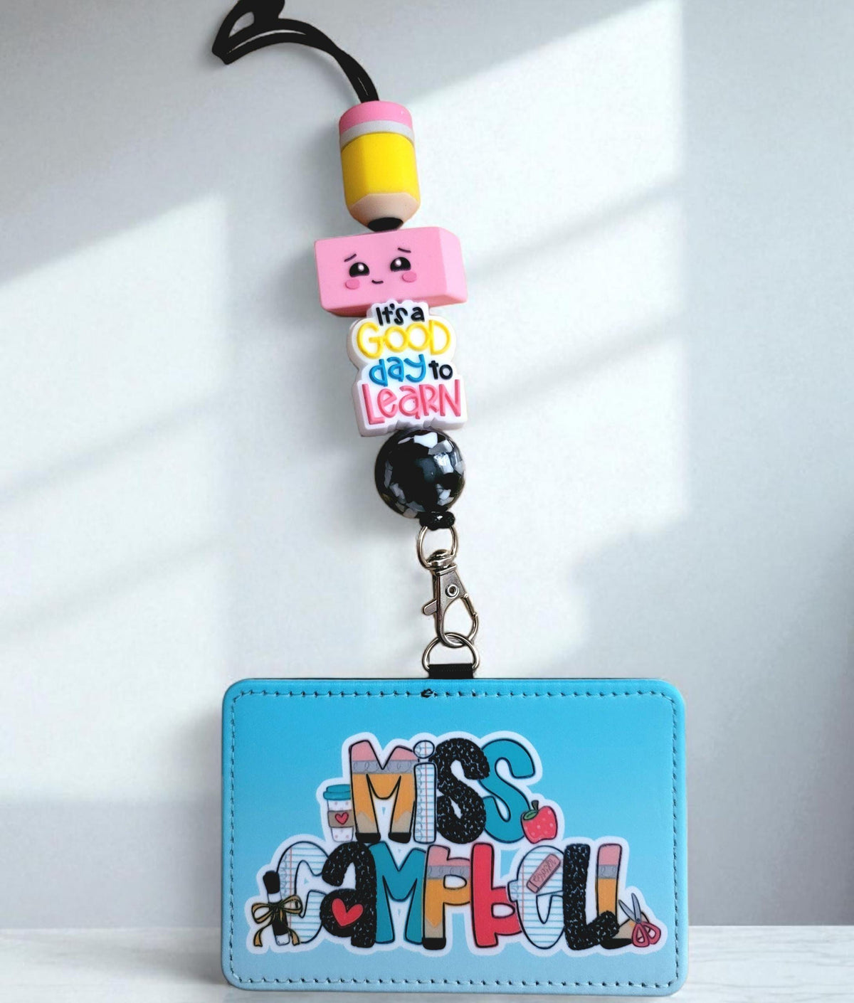 Mommie Peas Creations personalized blue faux leather teacher ID badge holder with a matching pencil-themed lanyard.