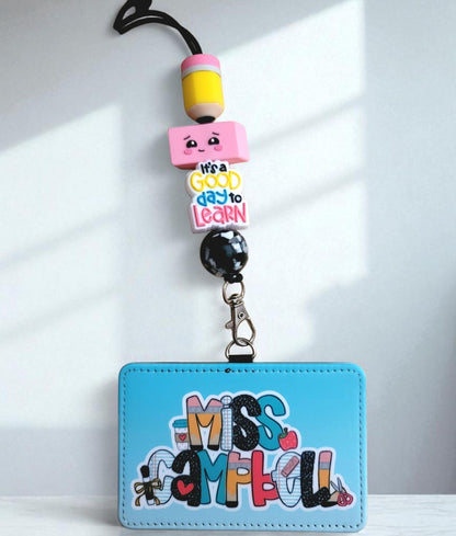 Mommie Peas Creations personalized blue faux leather teacher ID badge holder with a matching pencil-themed lanyard.