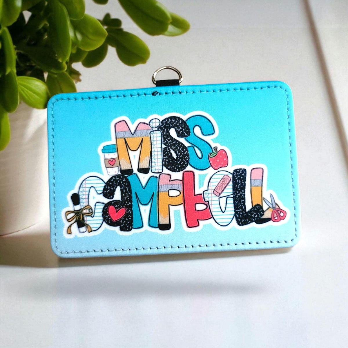 Mommie Peas Creations personalized light blue faux leather horizontal ID badge holder with teacher-themed motifs