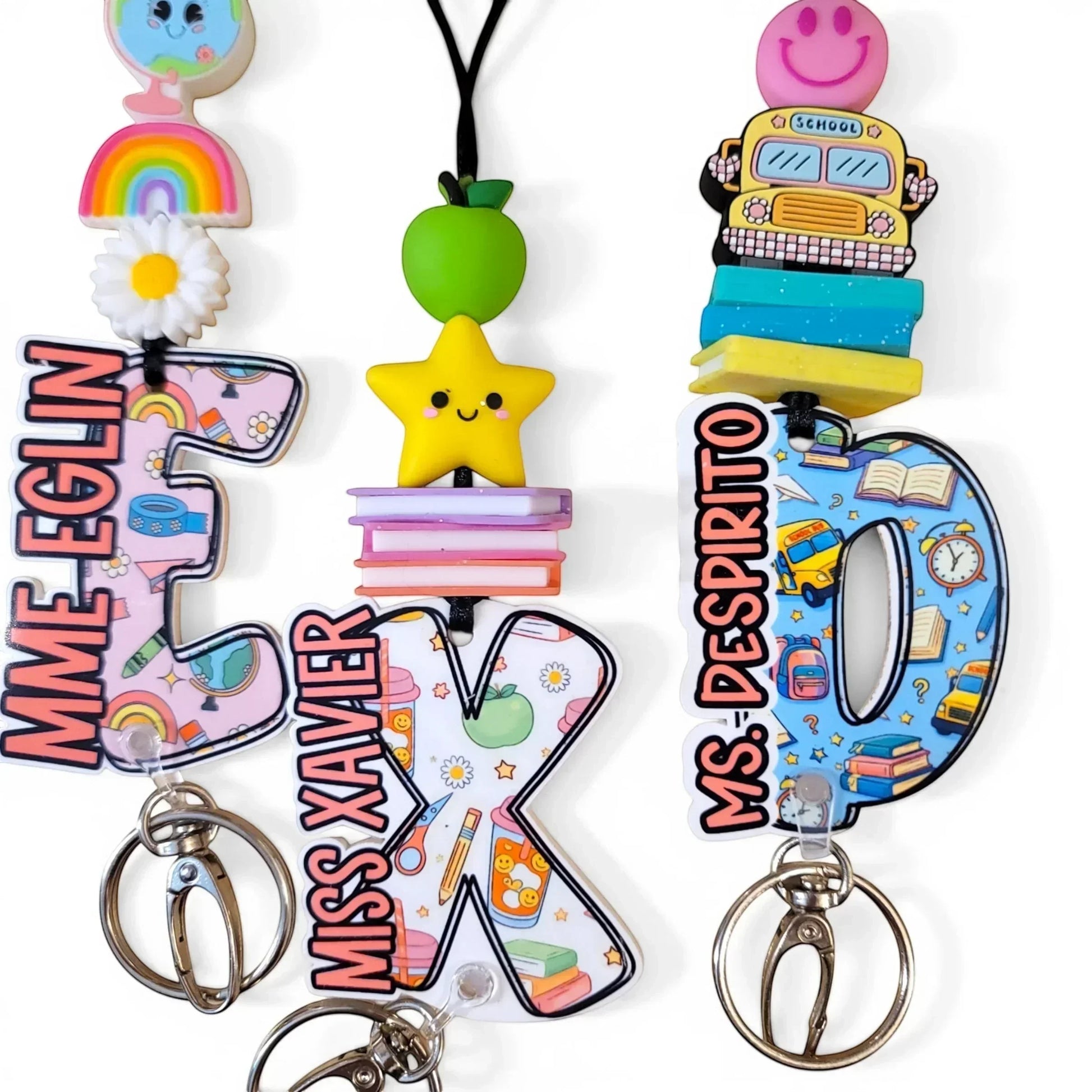 Colorful handmade teacher lanyards with personalized names, rainbow, apple, star, and school bus charms from Mommie Peas Creations