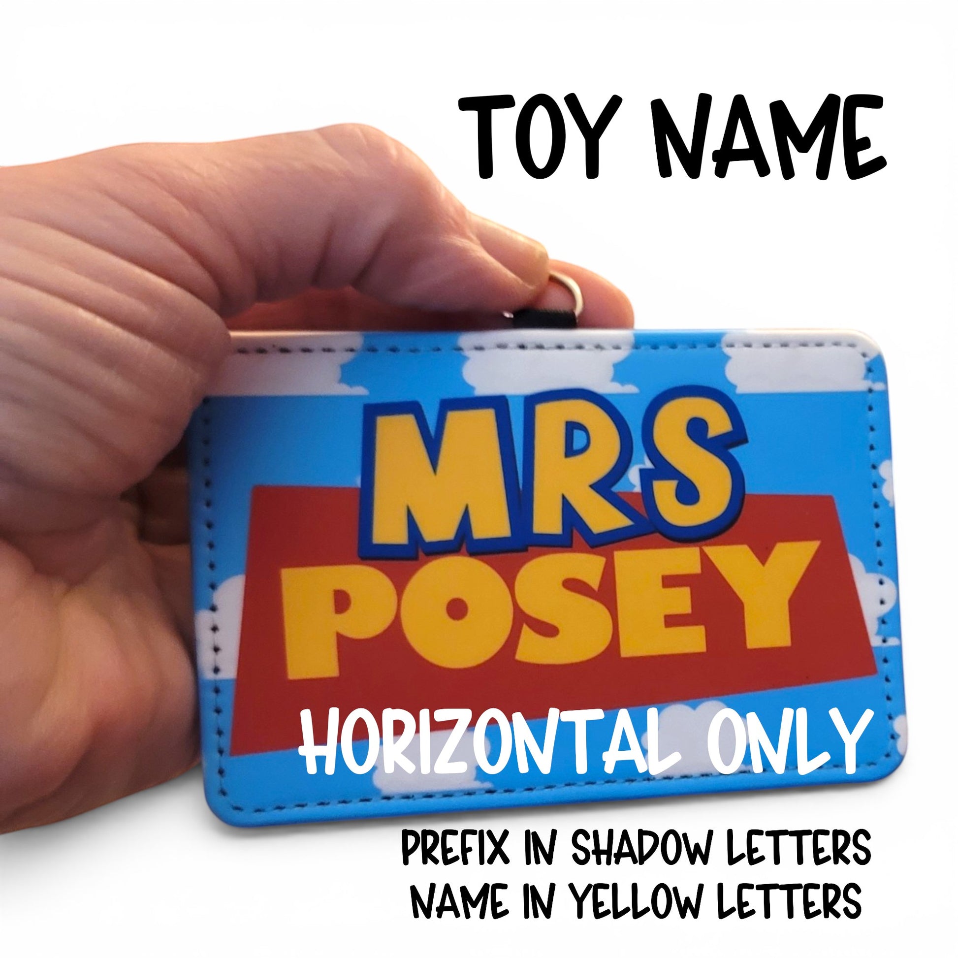 Mommie Peas Creations personalized Toy Story style ID holder with blue cloudy sky background and yellow name text.