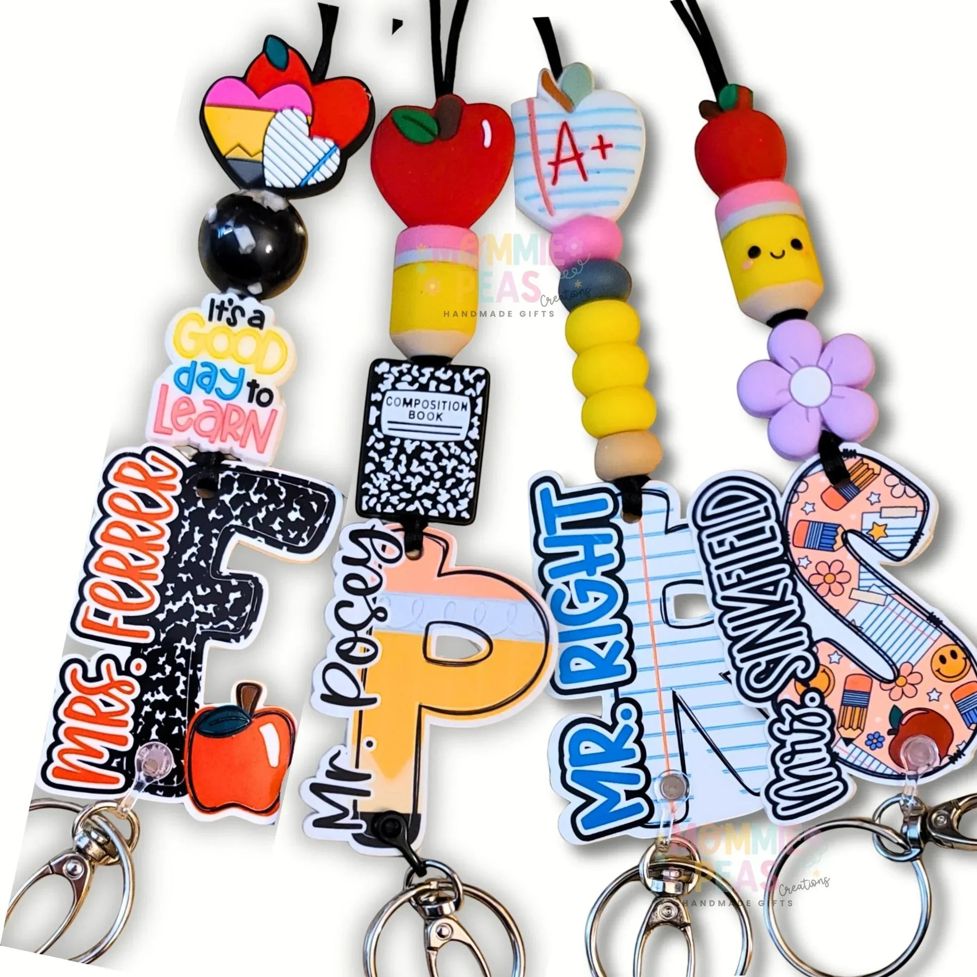Mommie Peas Creations personalized teacher lanyard with colorful silicone beads, acrylic charms like apples, pencils, and composition books, and custom letter charms.