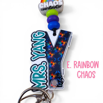 Mommie Peas Creations custom acrylic lanyard for Mrs. Yang, featuring a dark blue background with colorful handprints and the text "Chaos Coordinator" on a rainbow charm.