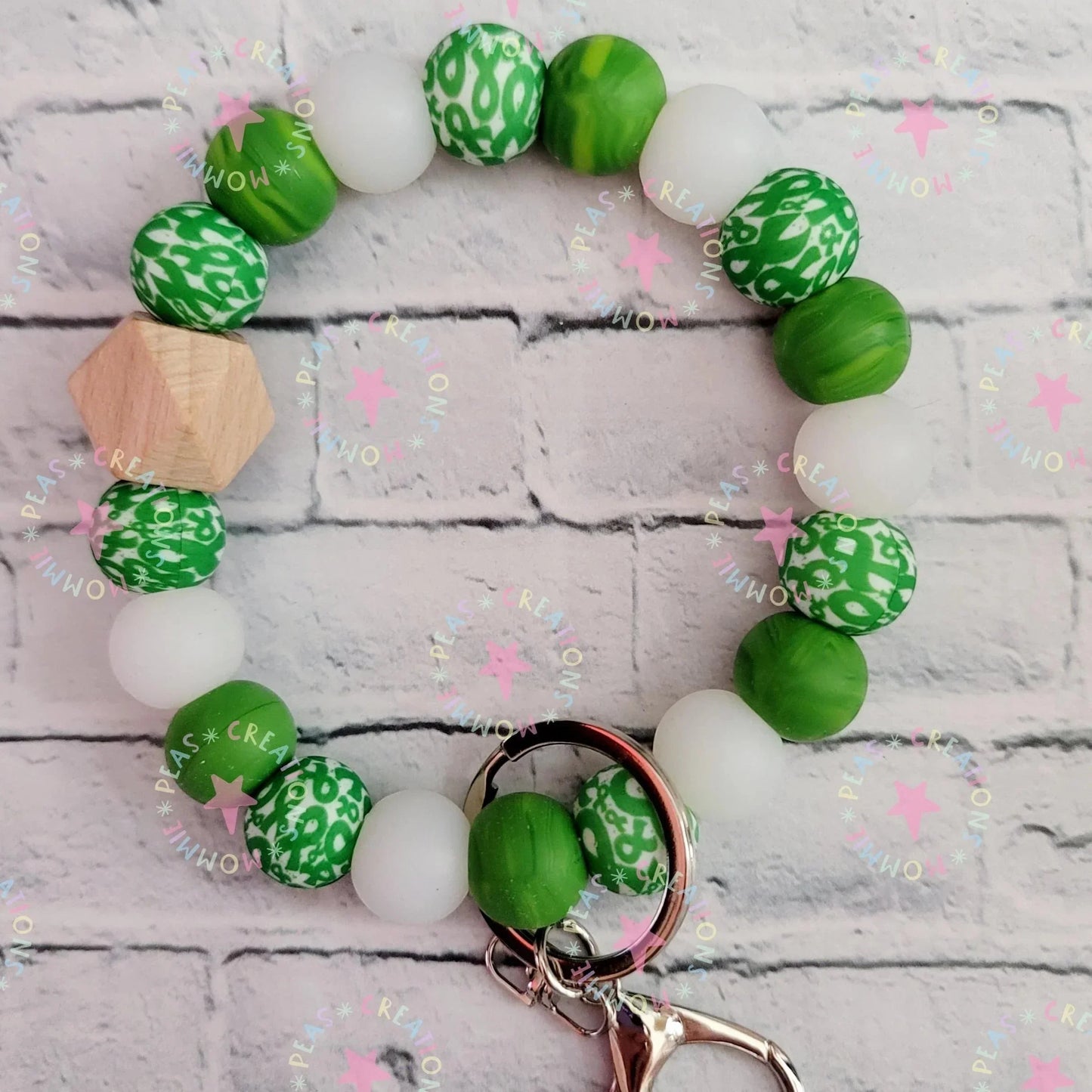 Mommie Peas Creations green and white silicone bead wristlet with wooden accent and green ribbon charm, featuring a swivel snap hook for keys.